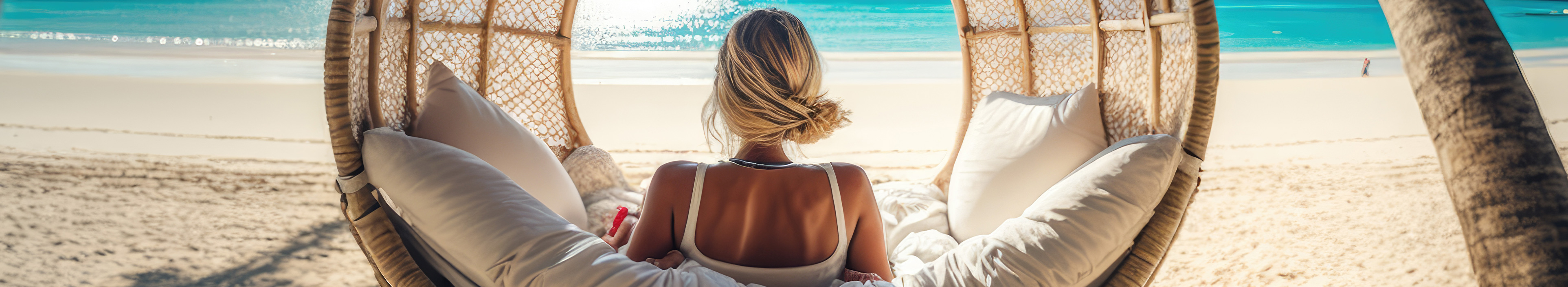 Eine Frau entspannt sich und genießt die Sonne im Urlaub am Strand in einer Korbhängematte
