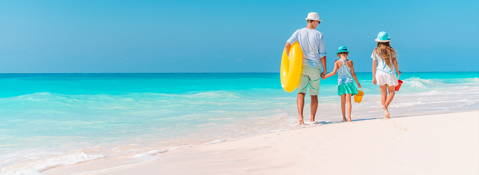 Eine Familie läuft im Urlaub am Strand entlang.