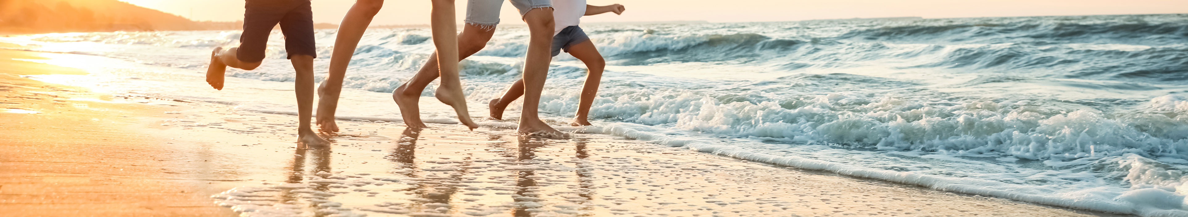 Eine Familie läuft an einem Strand während des Sonnenuntergangs.