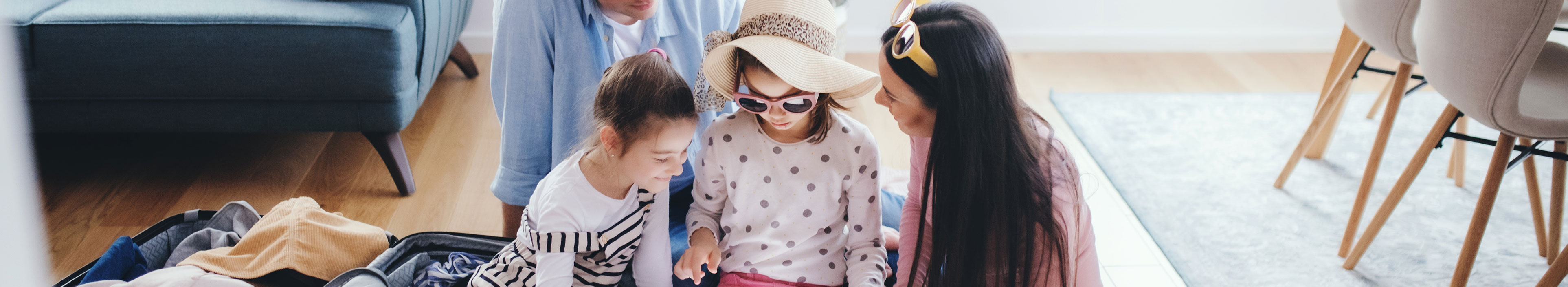 Eine Familie sitzt in einer Ferienwohnung, schauen zusammen auf ein Tablet.