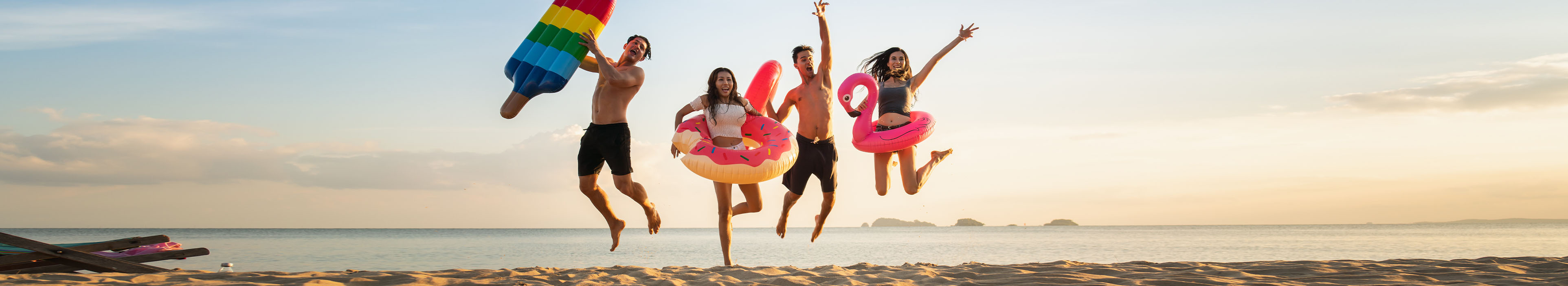 Eine Gruppe von Freunden springt am Strand in die Luft.
