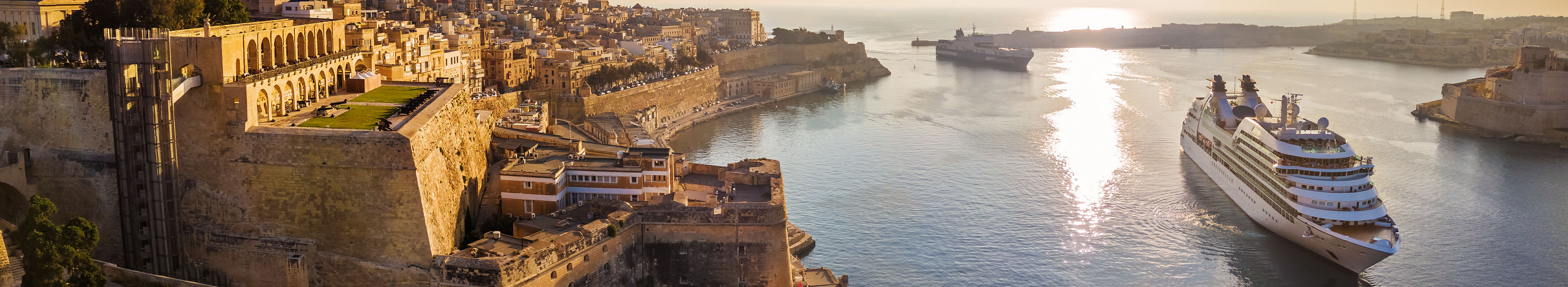 Zwei Kreuzfahrtschiffe fahren bei Sonnenaufgang in den Hafen bei Valletta, Malta.