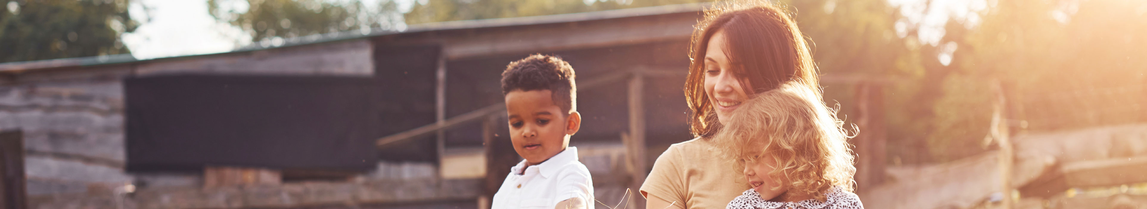 Urlaub auf dem Bauernhof: Eine Frau und zwei Kindern füttern eine Ziege.
