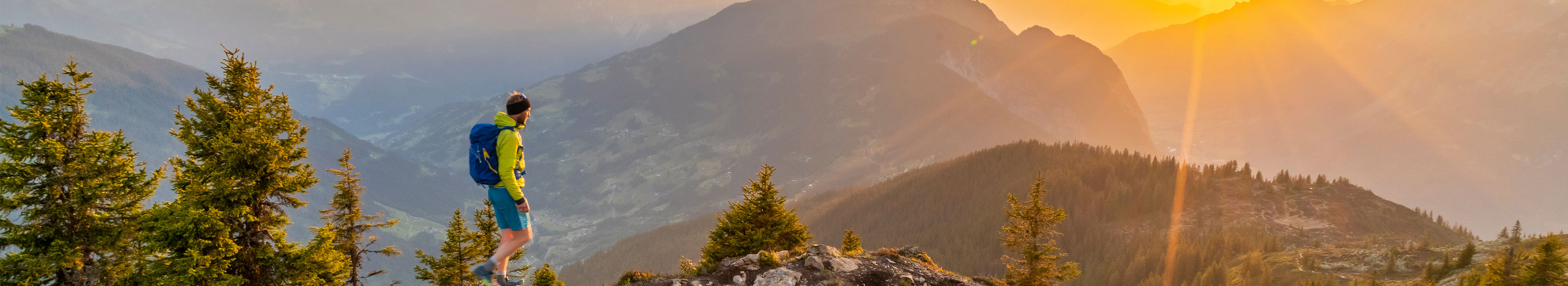 Ein Wanderer läuft während des Sonnenuntergangs in den Bergen.