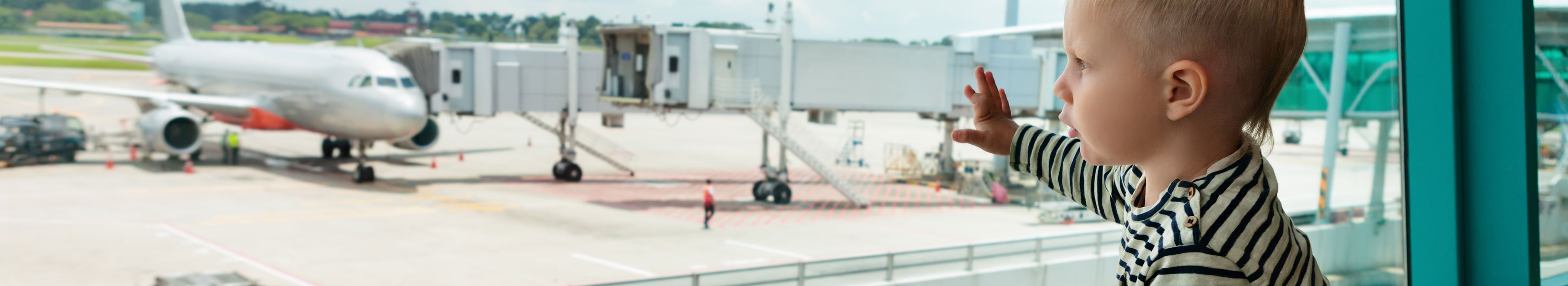 Ein Kleinkind am Flughafen, schaut auf ein Flugzeug