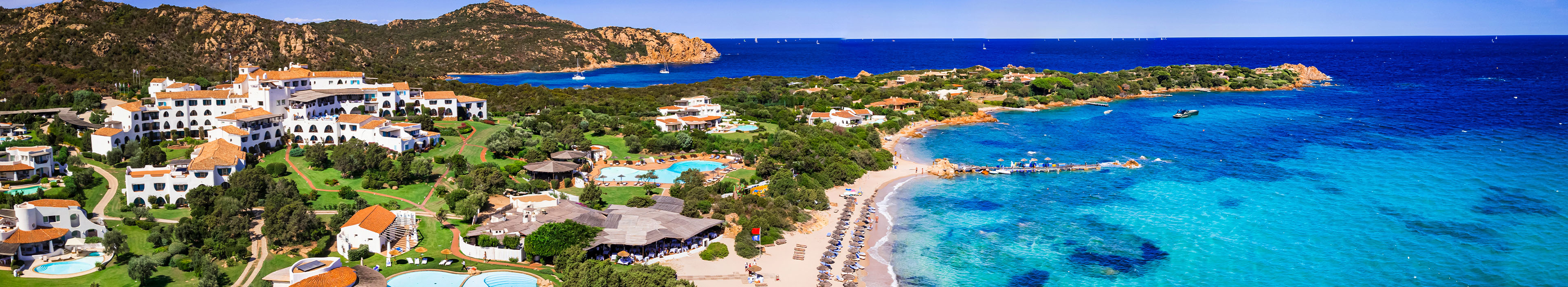 Blick auf einen sardischen Strand mit Hotels, Sonnenschirmen und Sonnenliegen.