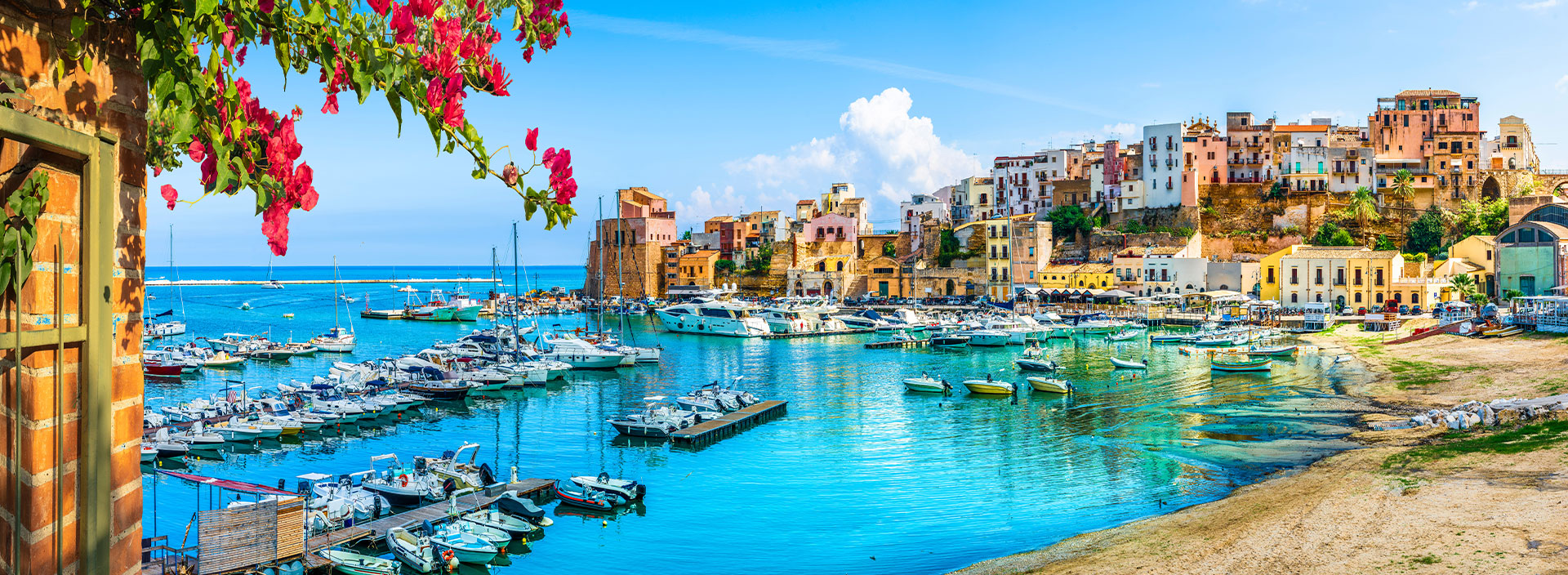 Urlaub Sizilien. Bunte Häuser mit Blick auf den Hafen.