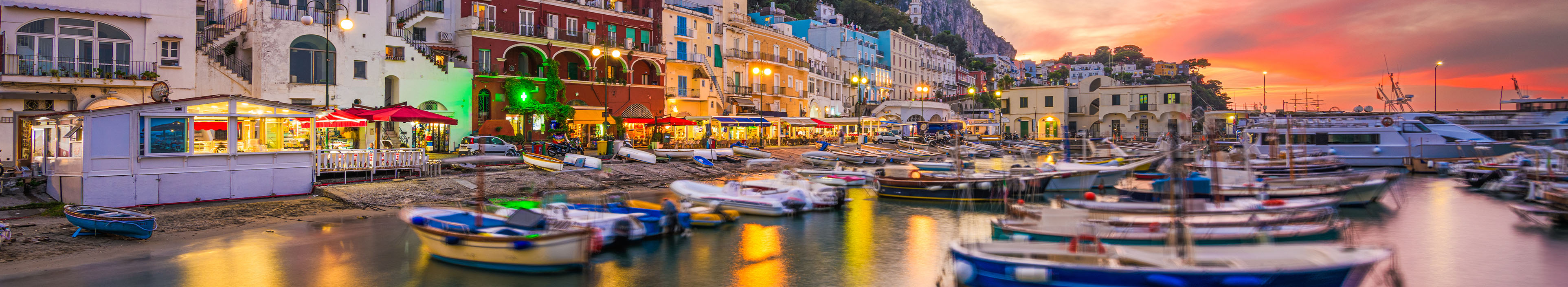 Promenade am Strand in Italien mit Hotels und Booten.
