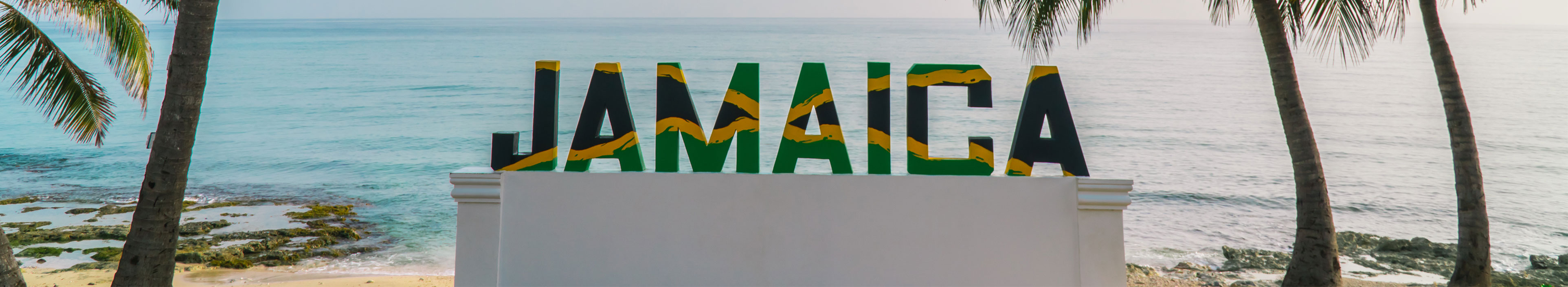 Jamaikanische Flagge mit Palmen an einem Strand.