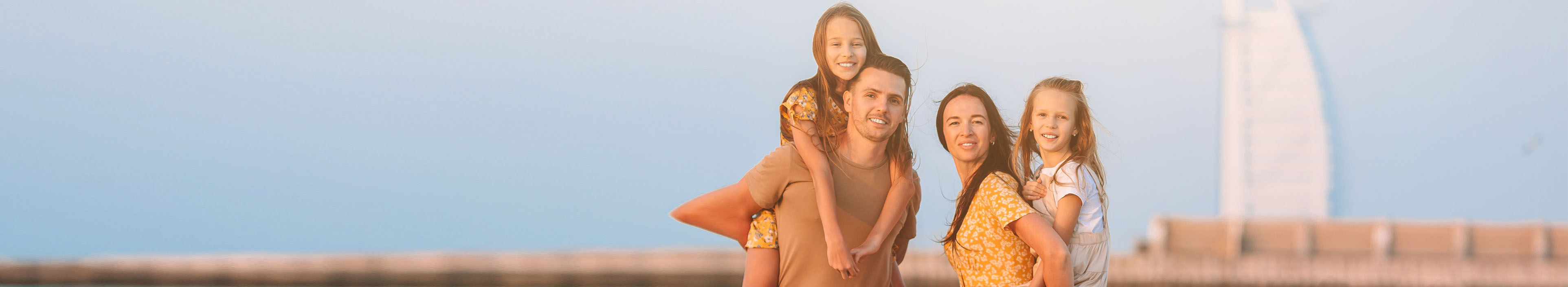 Eltern mit ihren beiden Töchtern vor dem Burj al Arab in Dubai, bei einem Familienurlaub.