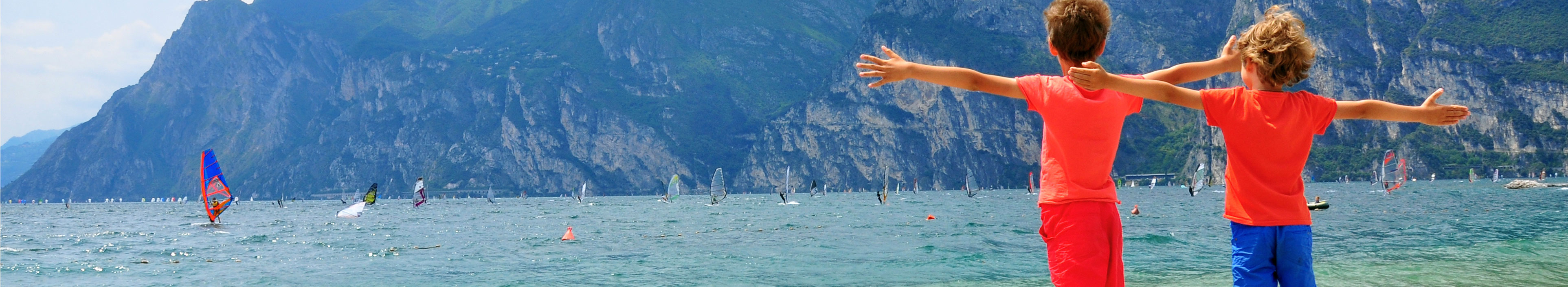 Kinder mit weit geöffneten Armen am Gardasee.