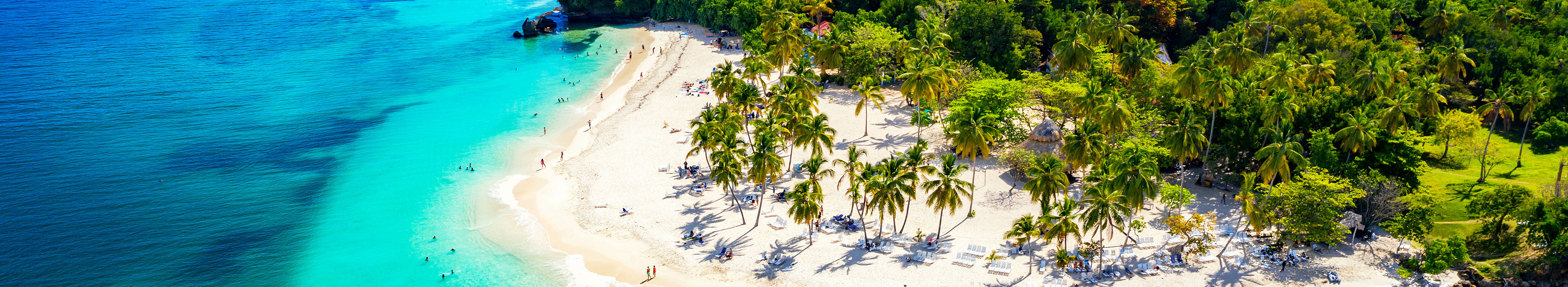 Urlaub Karibik. Weißer tropischer Sandstrand mit grünen Palmen und türkisblauem Meer.