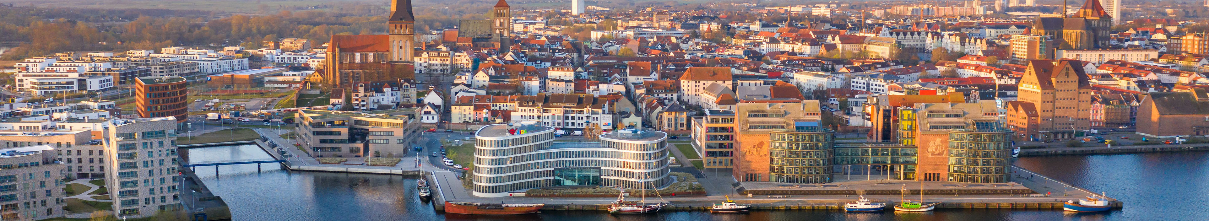 Panorama der Stadt Rostock - Luftaufnahme über die Warnow, Skyline bei Sonnenaufgang
